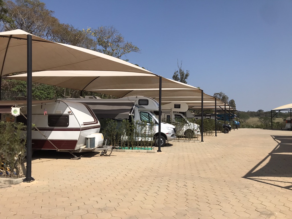 Trailer e motorhomes estacionados sob coberturas no Vila Chalés & RV Park, em Itu, São Paulo.
